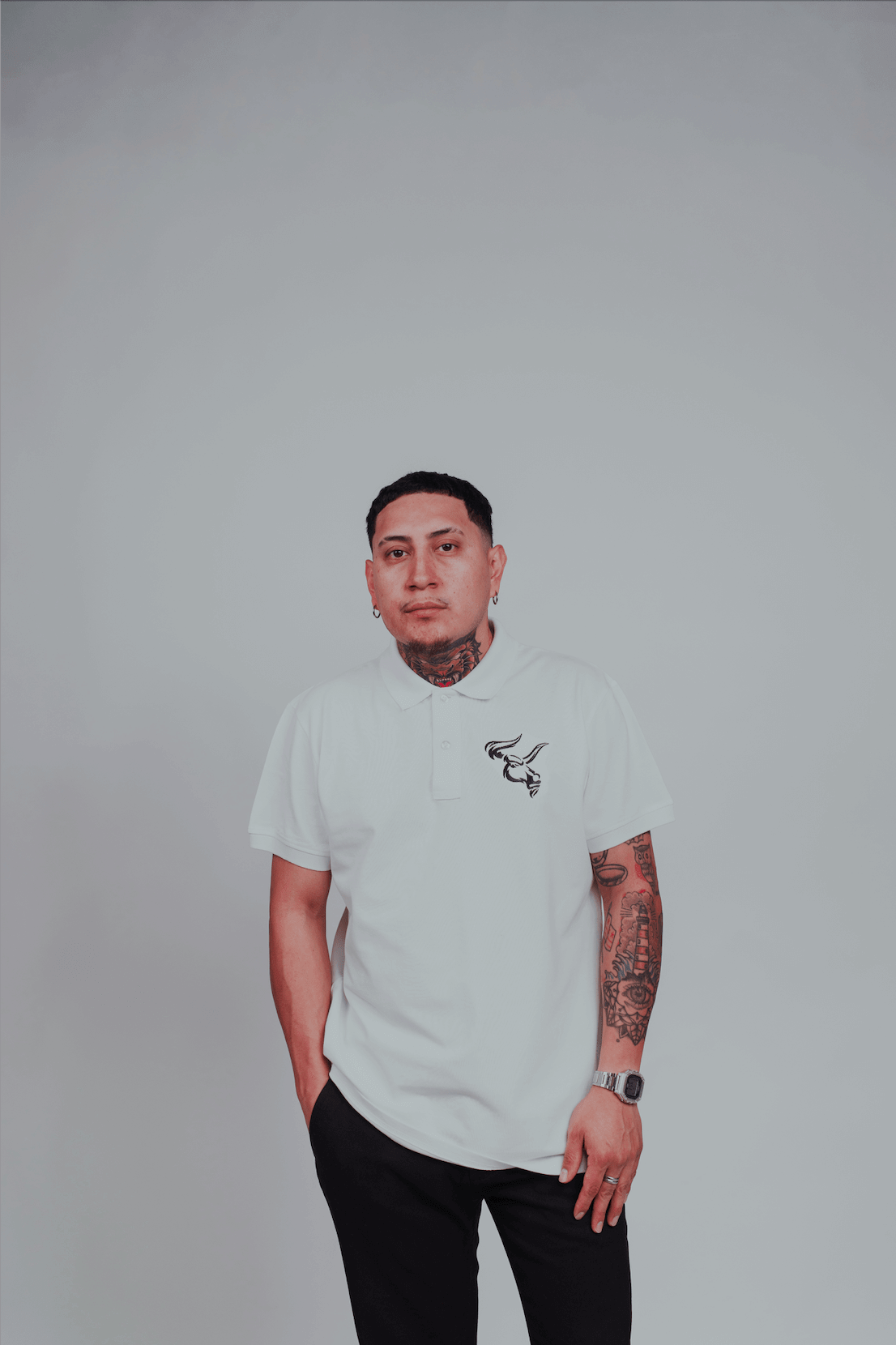 Man wearing BOS-BBS-100 Polo with embroidered bull head design, short sleeve, white color, and black pants, standing against a plain background.