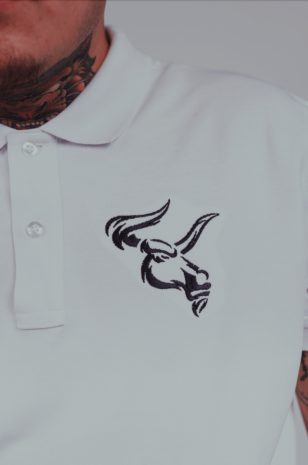 White polo shirt with big bull head embroidered design featuring curved letters and raised silicone logo.